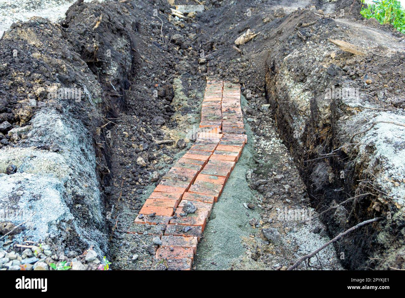 Posa e reinserimento di un frammento di una linea di cavi sotterranei di bassa profondità e messa a fuoco selettiva Foto Stock