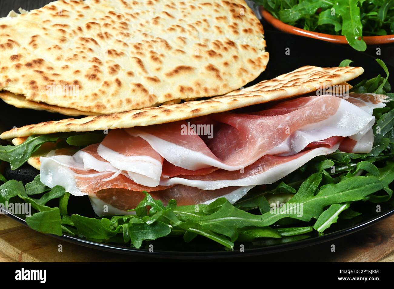 Piadina Romagnola con rucola e prosciutto è un popolare cibo di strada classico per un pasto veloce ed economico. Foto Stock