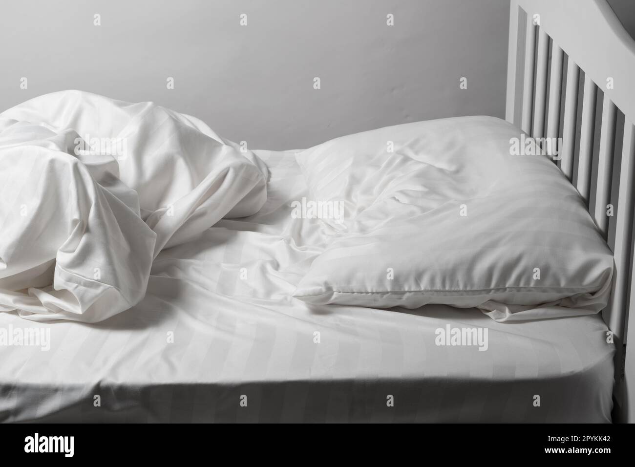 Letto non fatto in casa, lenzuola bianche in raso, letto bianco, cuscino e coperta Foto Stock