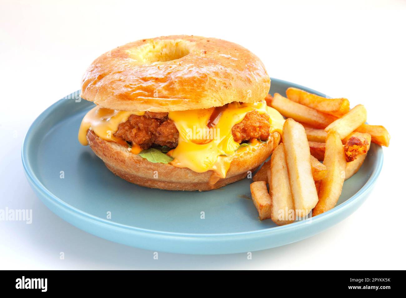 Hamburger di pollo fritto con brioche ciambella e patatine fritte serviti su un piatto blu. Foto Stock