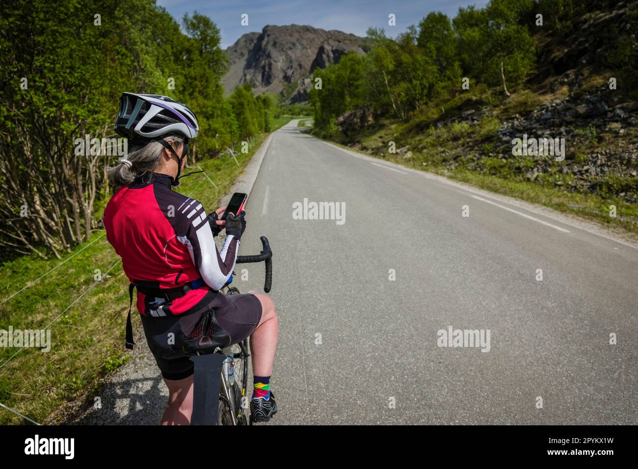 Ciclista femminile che controlla la sua rotta al telefono, Leka Island, Norvegia. Foto Stock