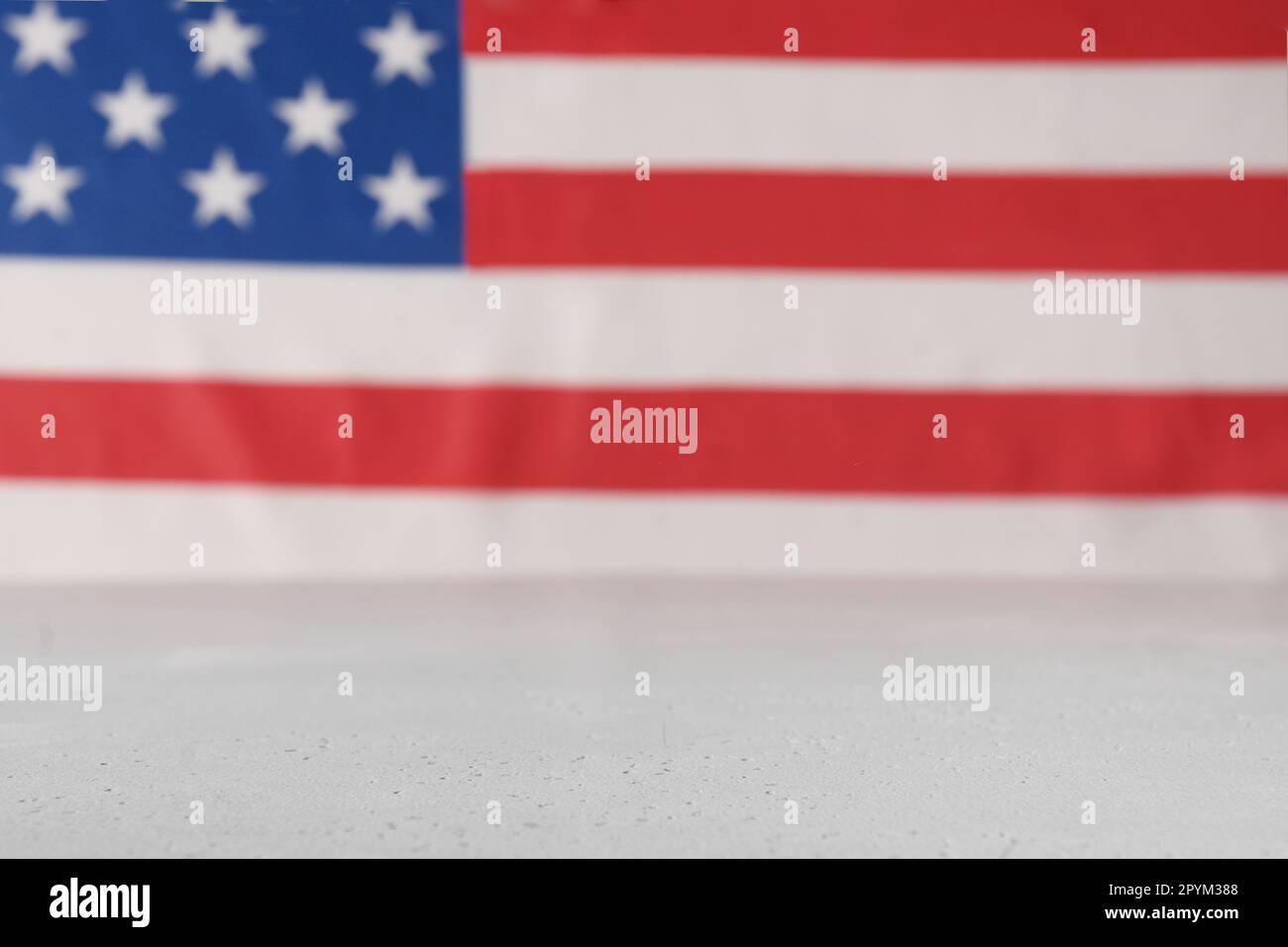 Bandiera americana come sfondo sfocato e tavolo bianco. Spazio di copia. 4th del concetto di festa di luglio. Foto Stock