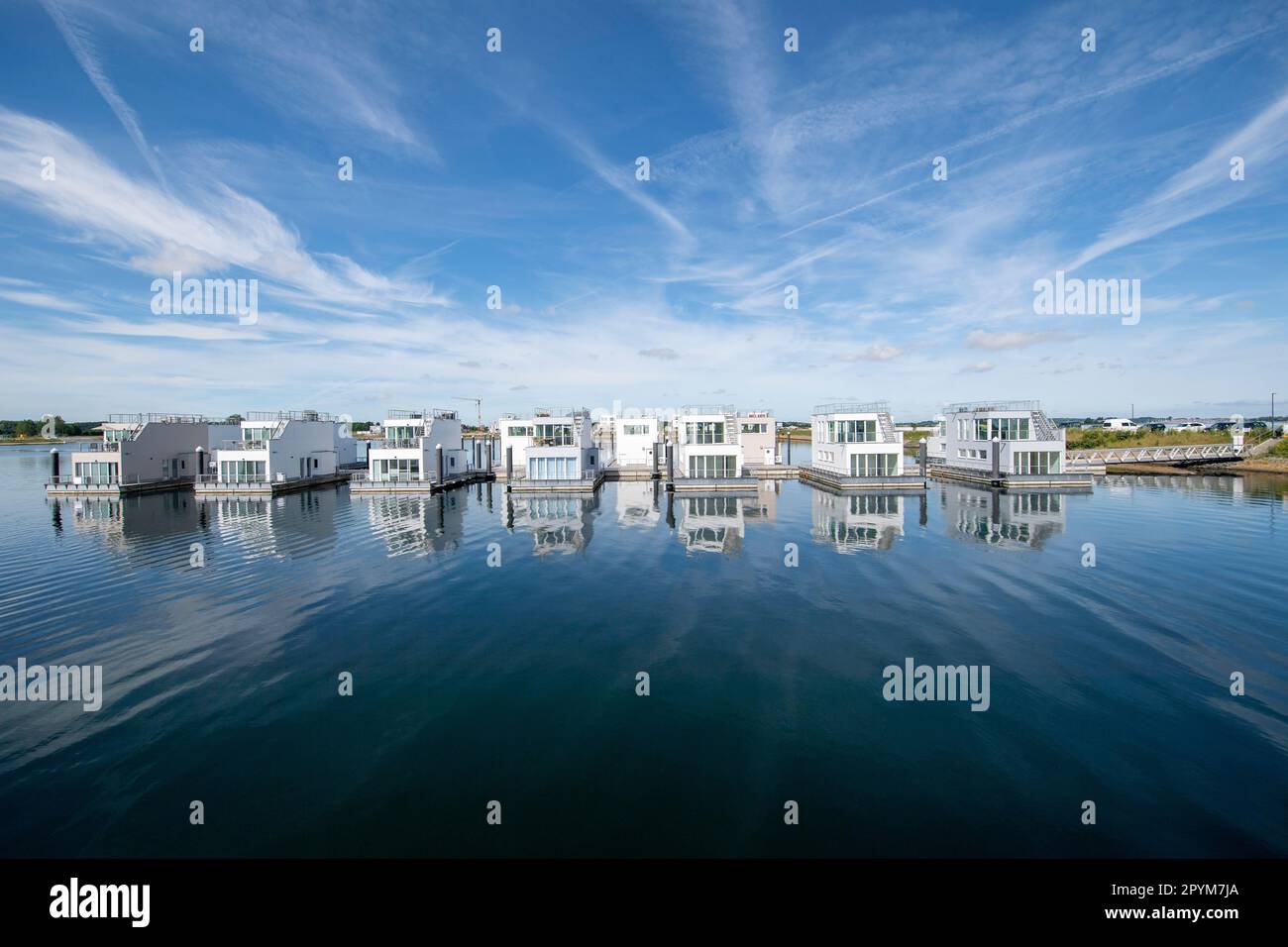 Foto panoramica della riflessione nell'acqua di diverse case costruite sulla riva del mare su un porto durante una giornata di sole. Foto Stock