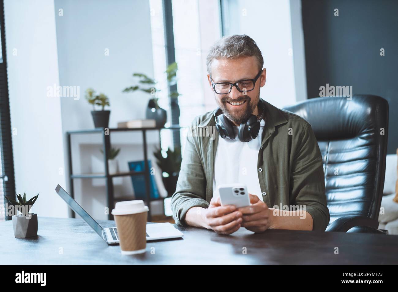 L'uomo europeo si sta rompendo in ufficio e usa il telefono per inviare messaggi di testo, illustrando il concetto di comunicazione facile. Ambiente di lavoro informale e rilassato. Foto di alta qualità Foto Stock