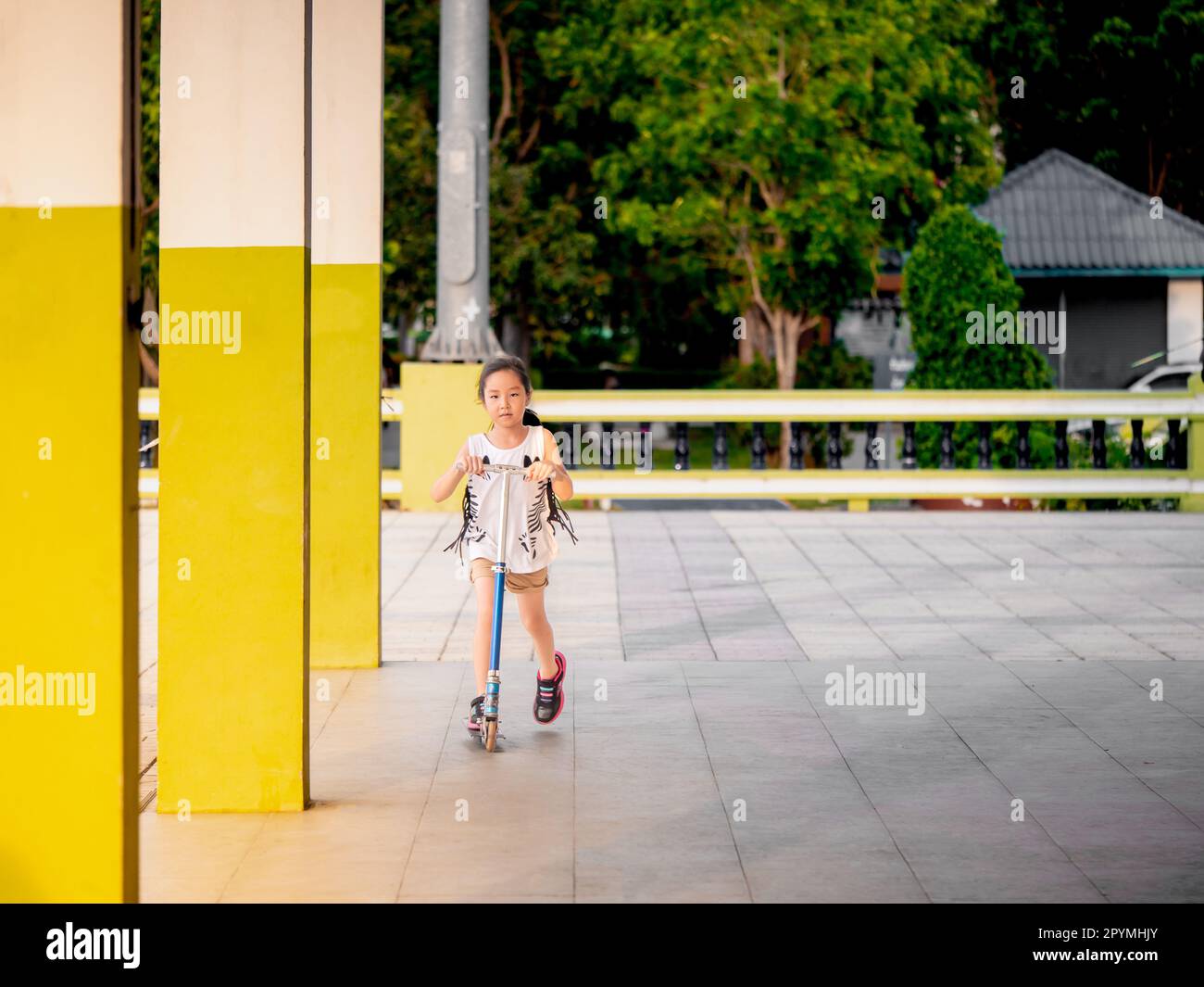 Piccola ragazza asiatica pilay scooter per bambini nel parco Foto Stock