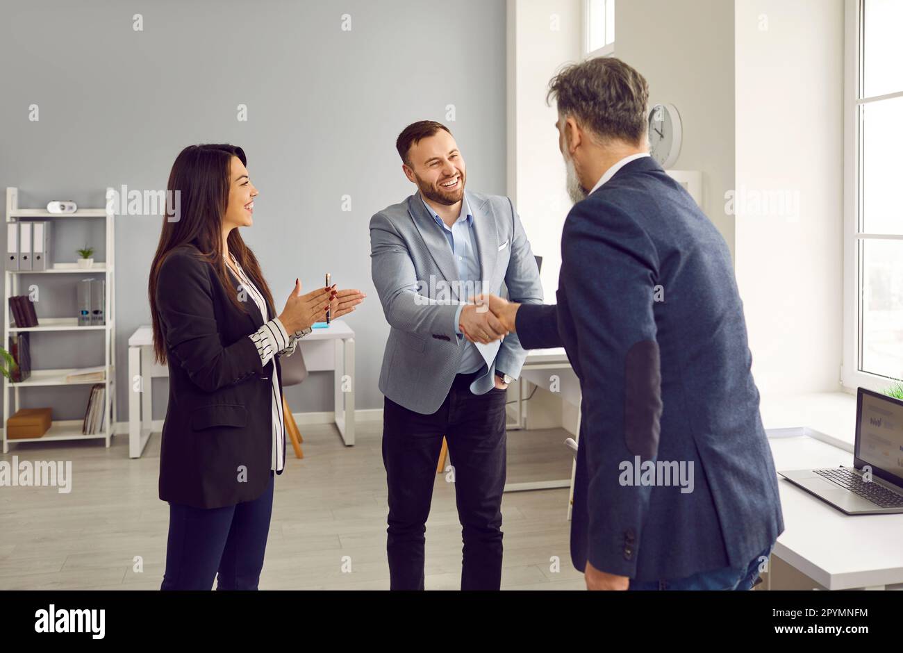 Due sorridenti partner commerciali maschili che scuotono le mani in ufficio Foto Stock