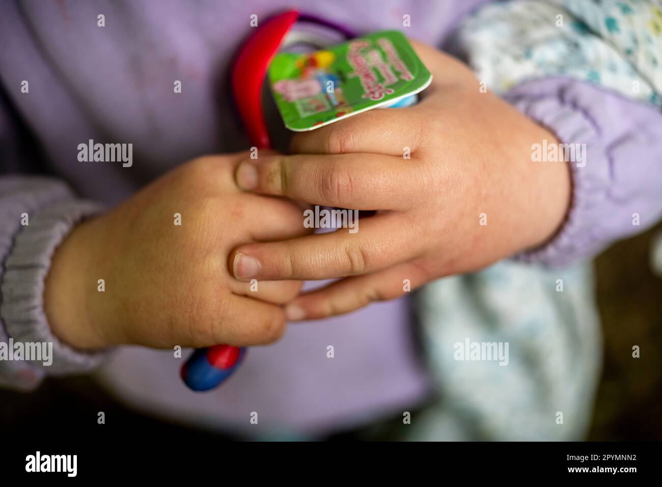 Un bambino le mani con yogurt e cucchiaio Foto Stock