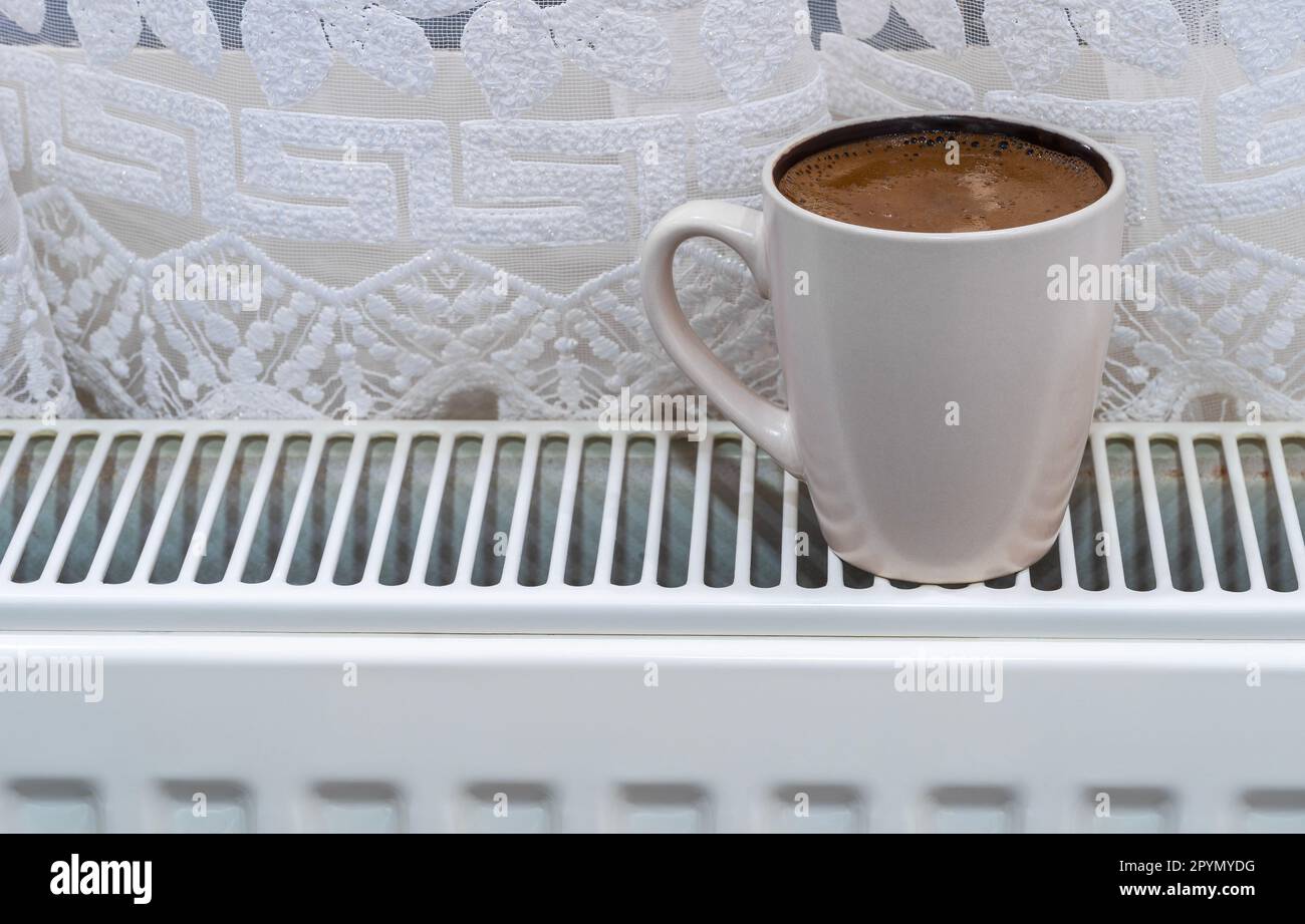 Una tazza di caffè su un radiatore caldo Foto Stock