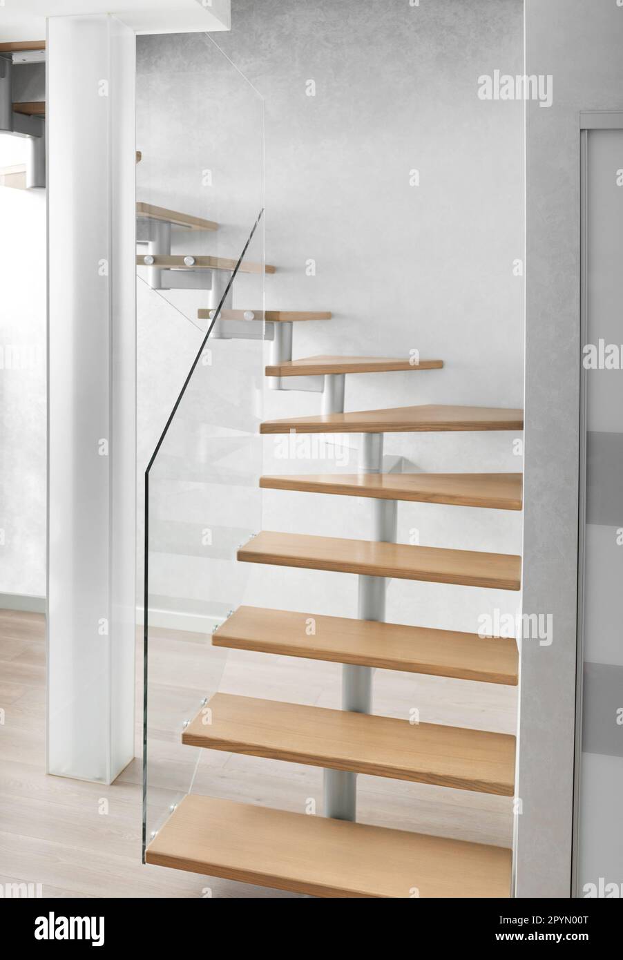 Scala con scale in legno e ringhiere in vetro nel moderno interno di un appartamento, casa. Scala di design in un appartamento su due livelli, vetro smerigliato Foto Stock