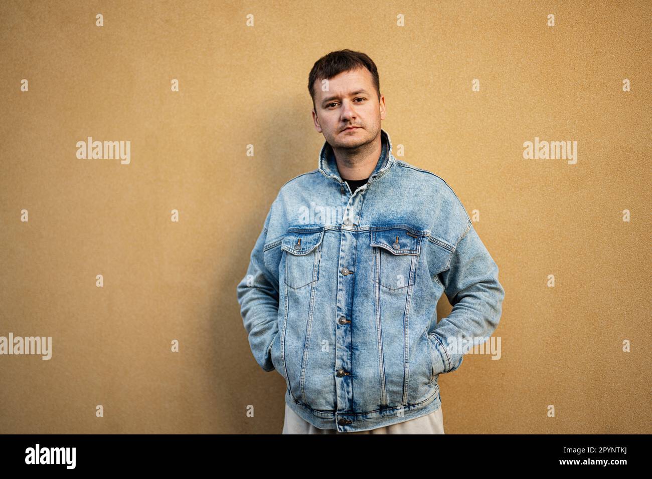 Ritratto di uomo elegante in giacca jeans contro parete gialla. Foto Stock