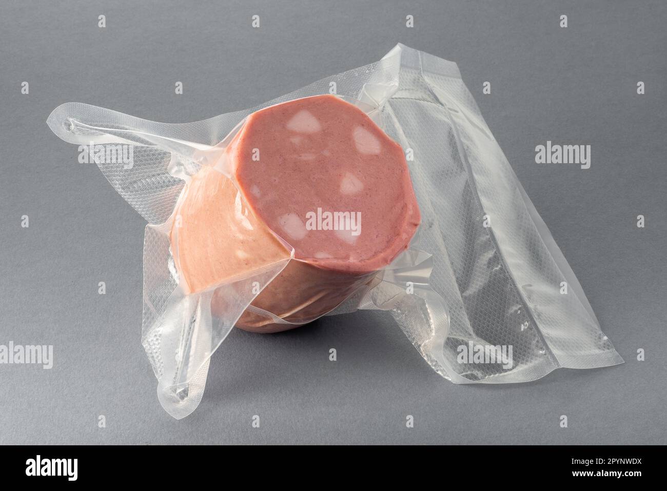 Salsiccia mortadella italiana in confezione sottovuoto per cucinare sous vide su fondo grigio Foto Stock