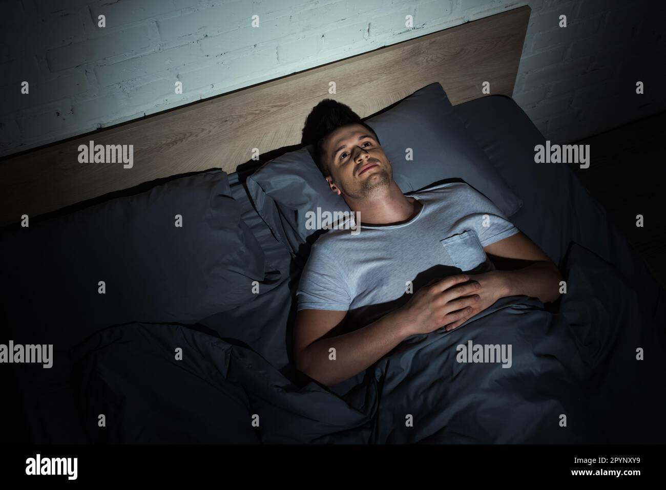 vista dall'alto di un giovane risvegliato con ptsd sdraiato sul letto e con insonnia di notte, immagine stock Foto Stock