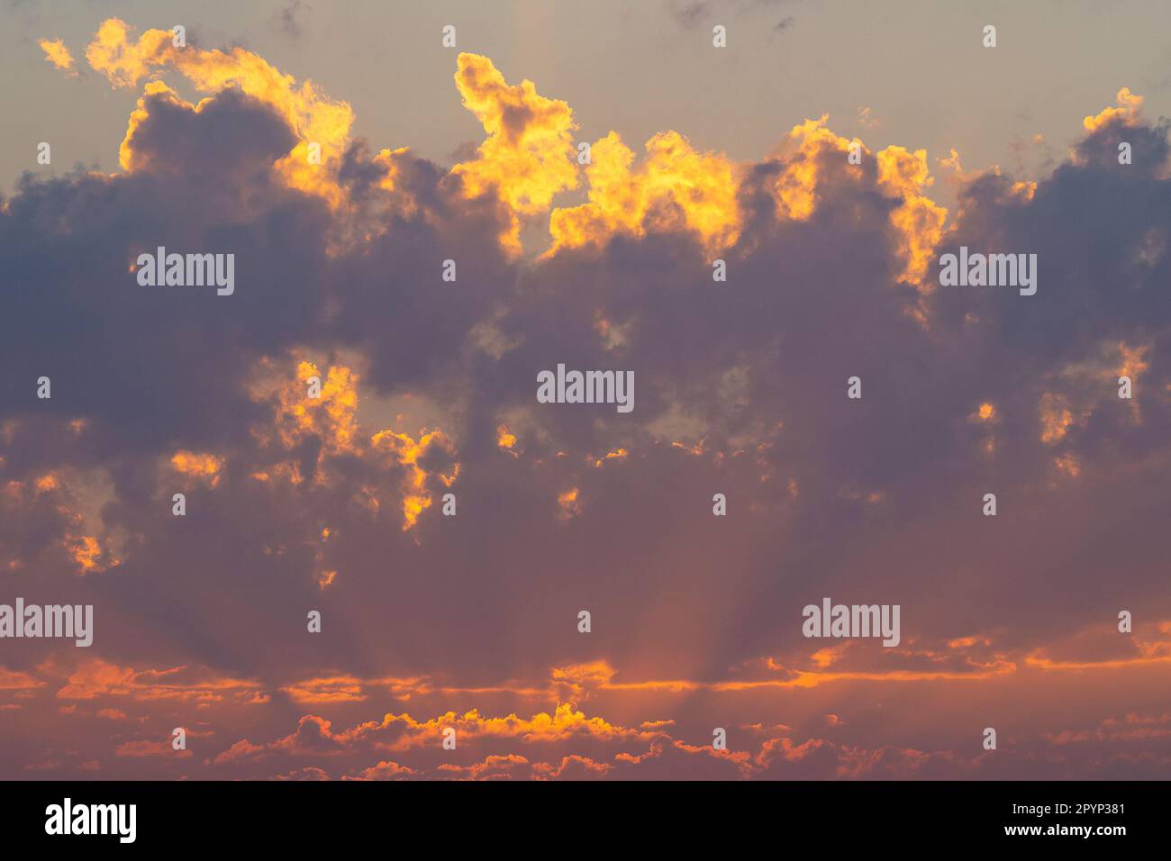 Il cielo parzialmente nuvoloso diventa di colore da arancione a rosso al tramonto Foto Stock