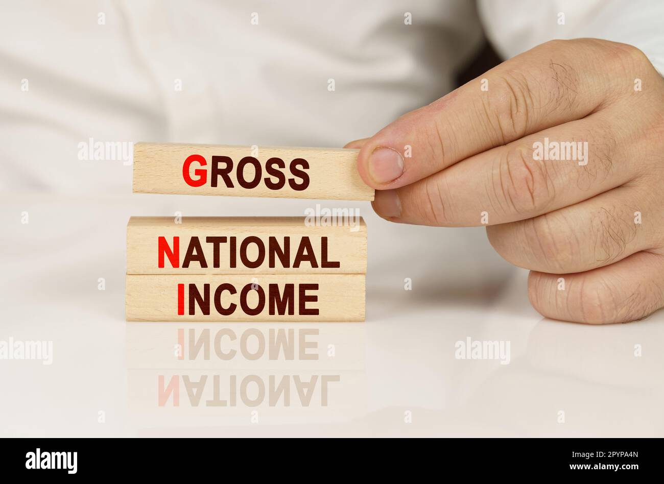 Concetto aziendale. Nelle mani di una persona e su una superficie riflettente sono i blocchi di legno con l'iscrizione - reddito nazionale lordo Foto Stock