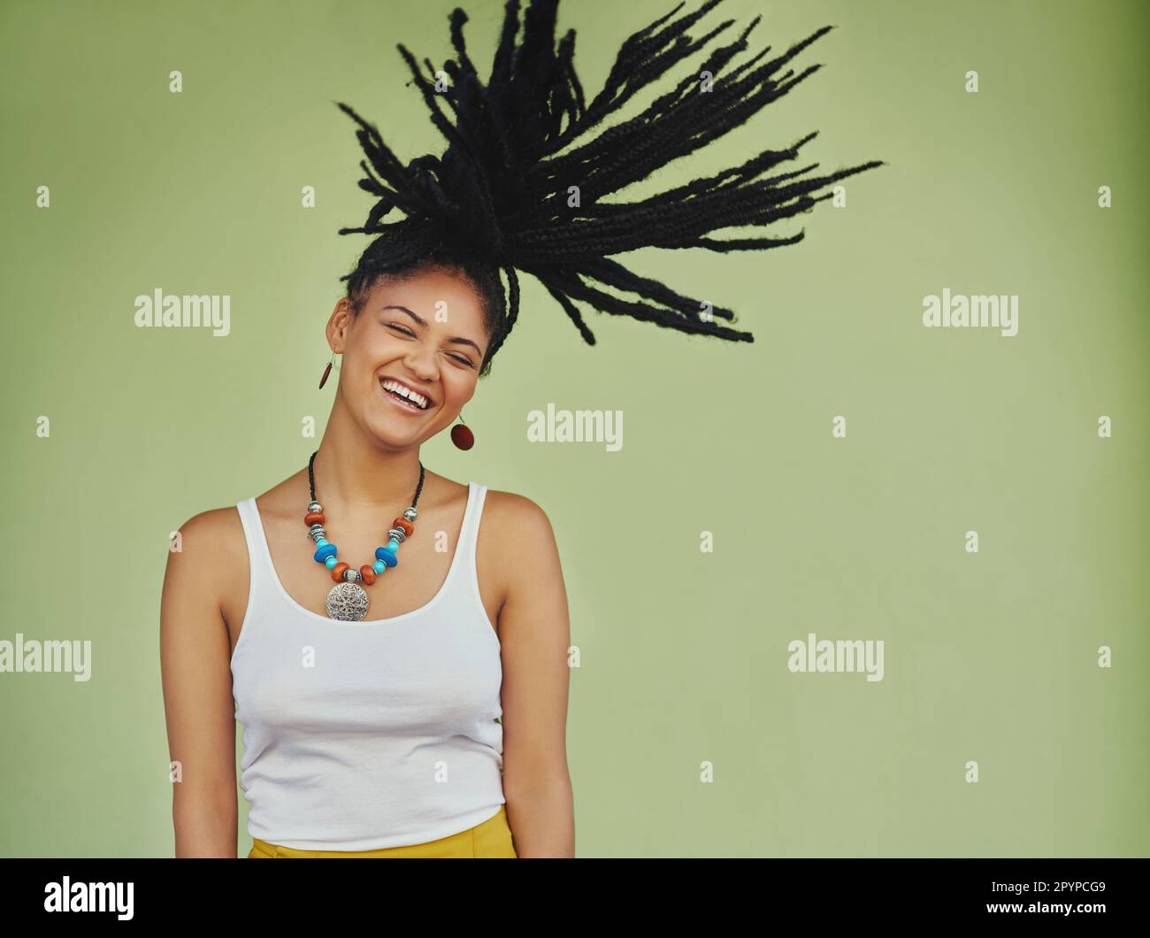 Lasciate che i vostri capelli a parlare. Studio shot di una giovane donna attraente che lancia i suoi capelli su uno sfondo verde. Foto Stock