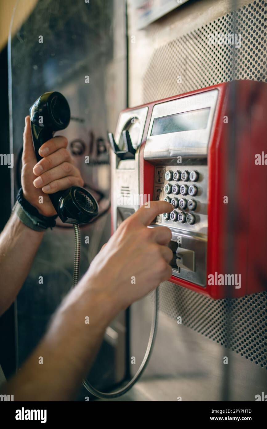 Persona che compone un numero di telefono su un telefono pubblico presso una cabina telefonica. Tecnologia delle telecomunicazioni di vecchia scuola. Foto Stock