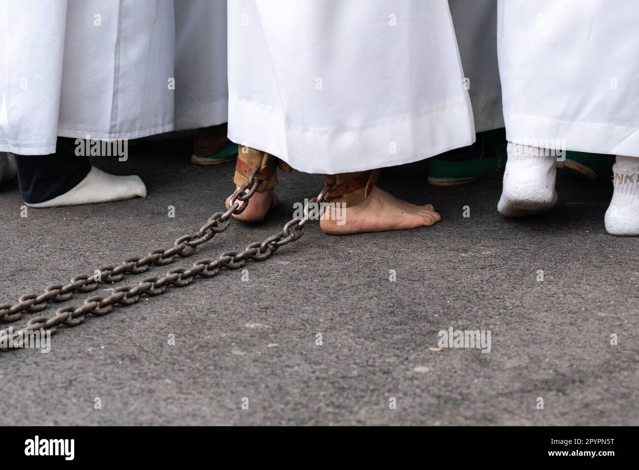 Un Nazareno barefalo trascina una catena dalla caviglia mentre porta una massiccia piattaforma con una statua di Gesù Cristo e dei Romani in una processione durante la settimana Santa o Semana Santa, 5 aprile 2023 a Ronda, Spagna. Ronda, insediata per la prima volta nel 6th° secolo a.C., ha tenuto le processioni della settimana Santa per oltre 500 anni. Foto Stock