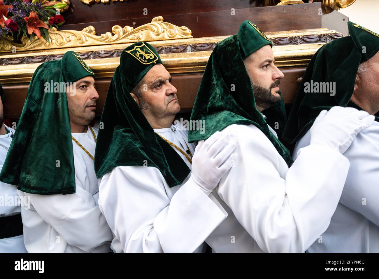 I Nazareno che indossano cappelli verdi trasportano una piattaforma massiccia con una statua di Gesù Cristo e dei Romani in una processione durante la settimana Santa o Semana Santa, 5 aprile 2023 a Ronda, Spagna. Ronda, insediata per la prima volta nel 6th° secolo a.C., ha tenuto le processioni della settimana Santa per oltre 500 anni. Foto Stock