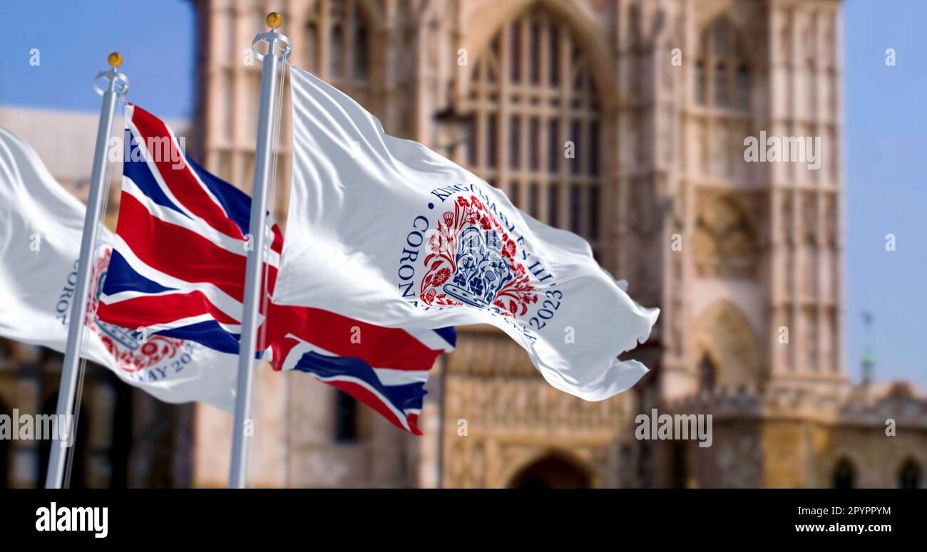 Londra, Regno Unito, aprile 2023: Bandiere con l'emblema dell'incoronazione di Re Carlo III e del Regno Unito che sventolano con Westminster Abbey sullo sfondo. Illustr Foto Stock