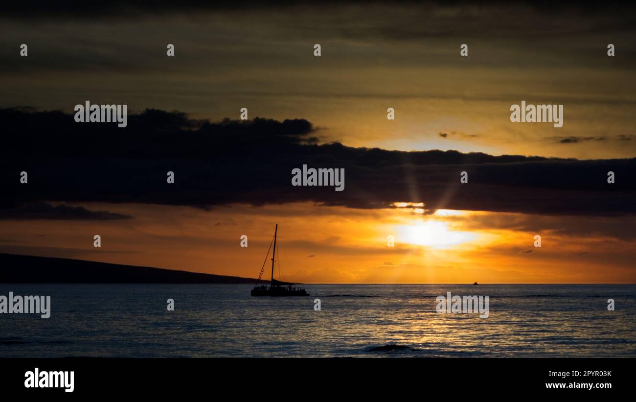 Acque calme e una bella silhouette al tramonto una barca a vela lungo la costa di Kaanapali a Maui, Hawaii. Foto Stock