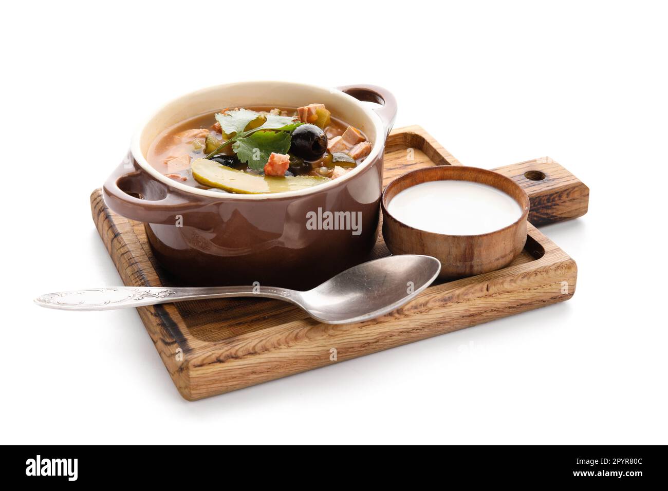 Pentola di gustosa zuppa di Hodgepodge con panna acida su sfondo bianco Foto Stock