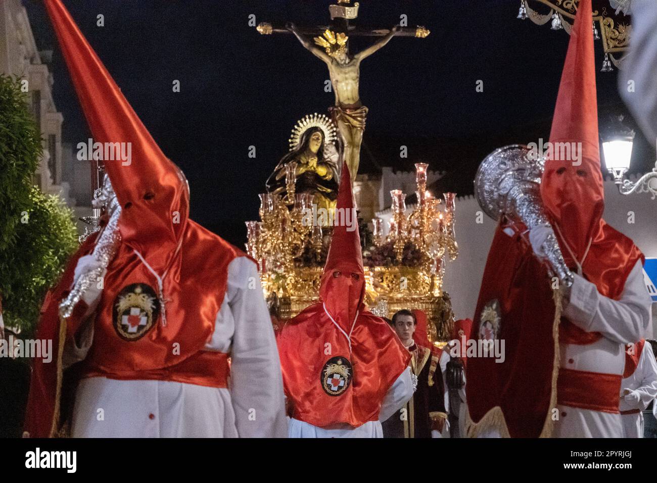 Le cofradias che indossano cappe a forma di cono rosso portano una piattaforma gigante con la Crocifissione durante la processione silenziosa di mezzanotte che segna il Venerdì Santo alla settimana Santa o Semana Santa, 6 aprile 2023 a Ronda, Spagna. Ronda, insediata per la prima volta nel 6th° secolo a.C., ha tenuto le processioni della settimana Santa per oltre 500 anni. Foto Stock