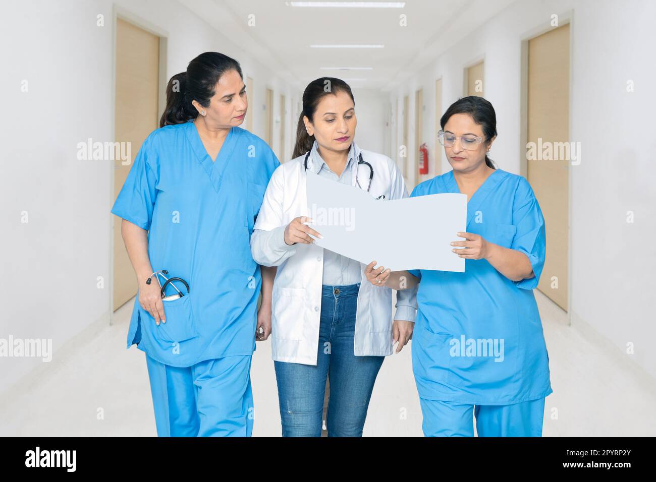 Medico femminile indiano e personale infermieristico discutere rapporto medico in corridoio ospedale, concetto di assistenza sanitaria. Foto Stock
