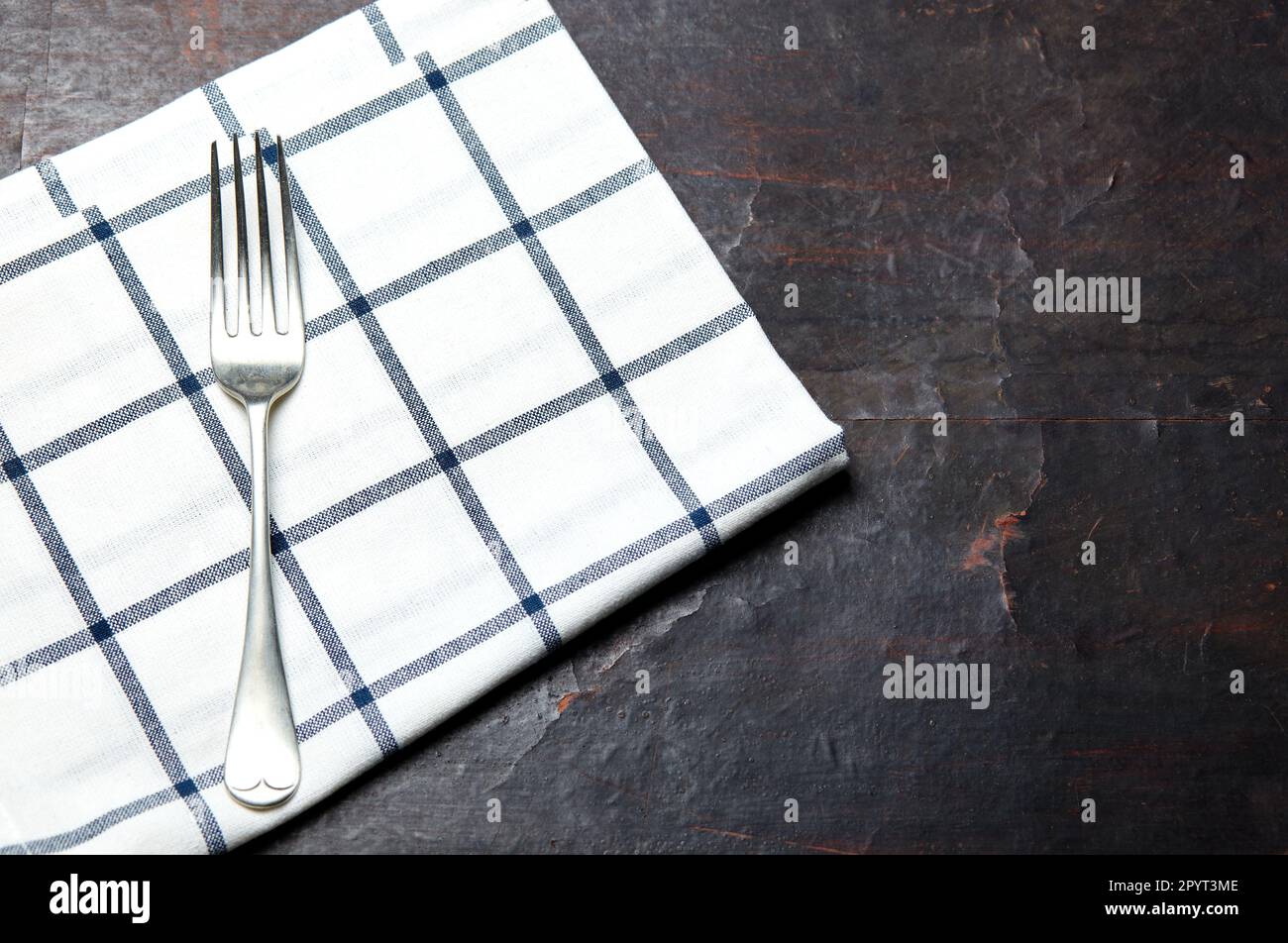 Tavolo da cucina con asciugamano e forchetta. Tavolo di legno con un tovagliolo di stoffa. Sopra la vista con spazio di copia, posizionare per il testo Foto Stock