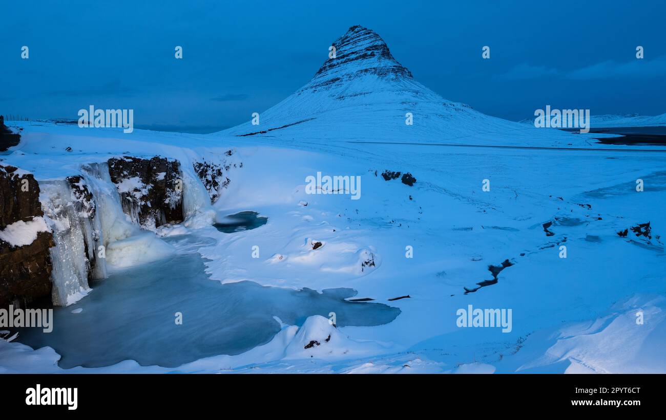 Cascata ghiacciata di fronte all'iconica montagna all'ora blu Foto Stock