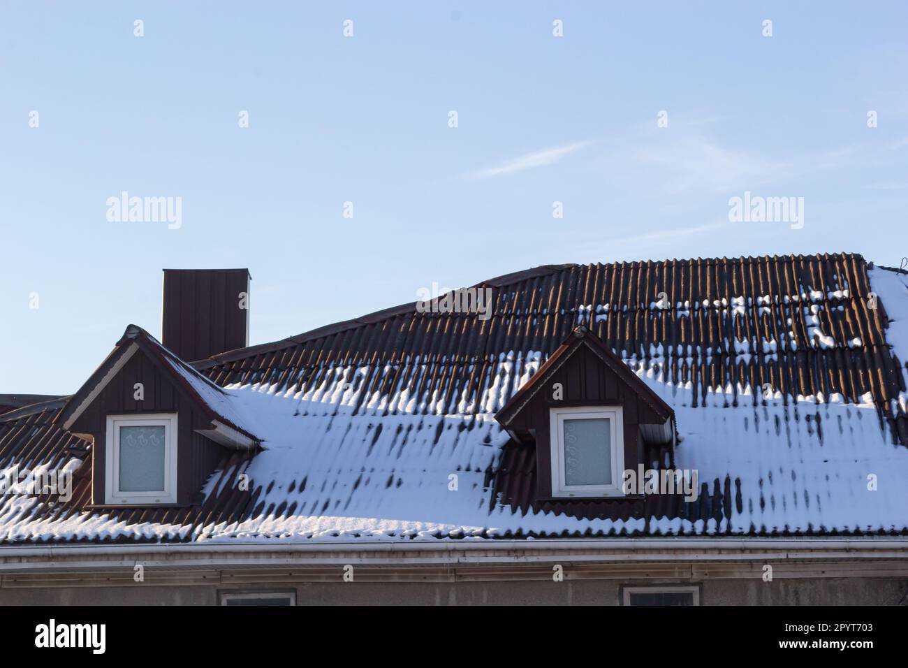 Neve sul tetto di una mattonella di metallo rossa e marrone di una casa europea. Foto Stock