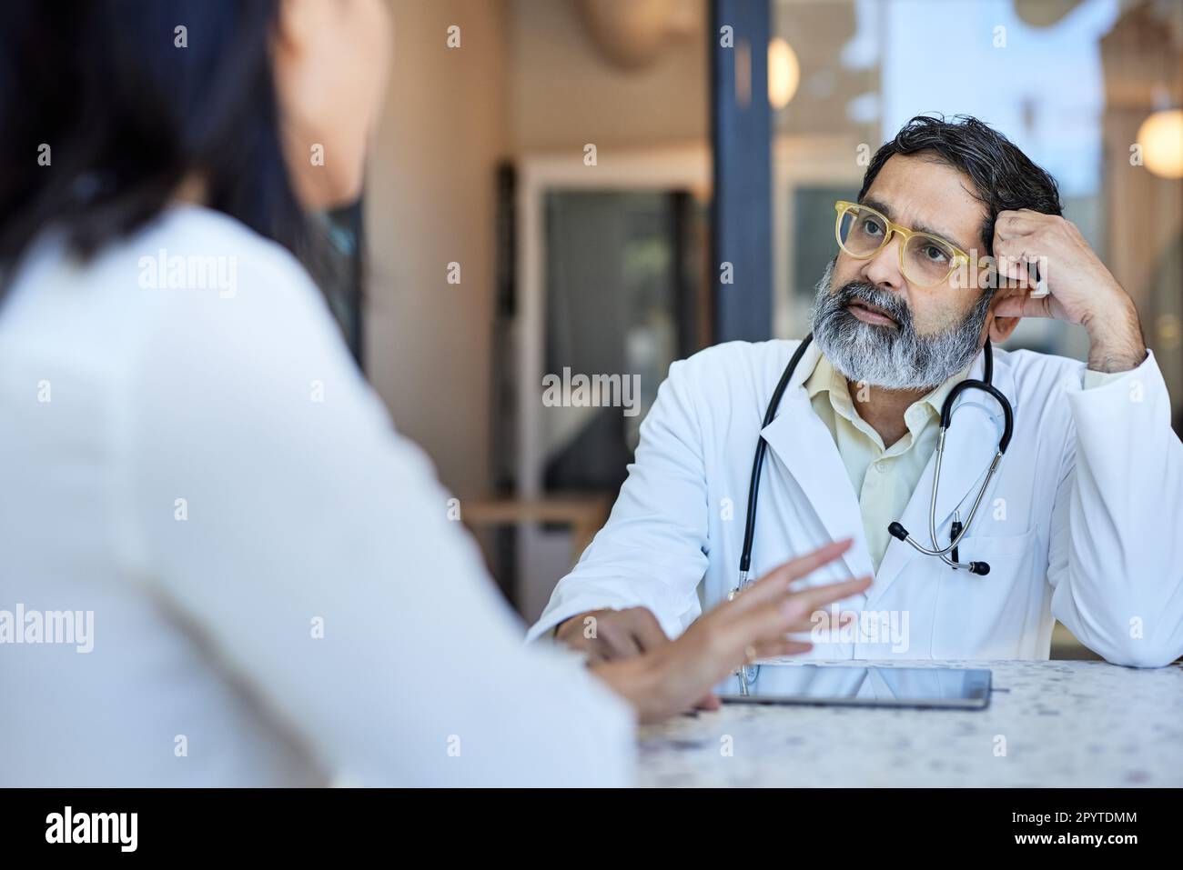 Medico maturo che ascolta la paziente seduta in clinica Foto Stock