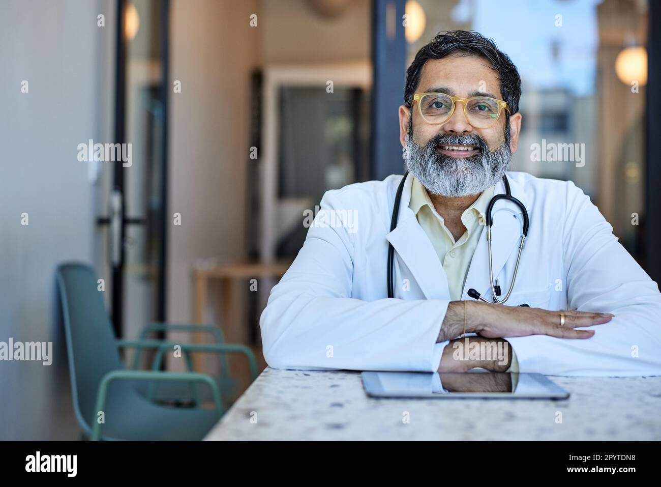 Ritratto di un operatore sanitario maschile sorridente seduto alla scrivania in clinica Foto Stock