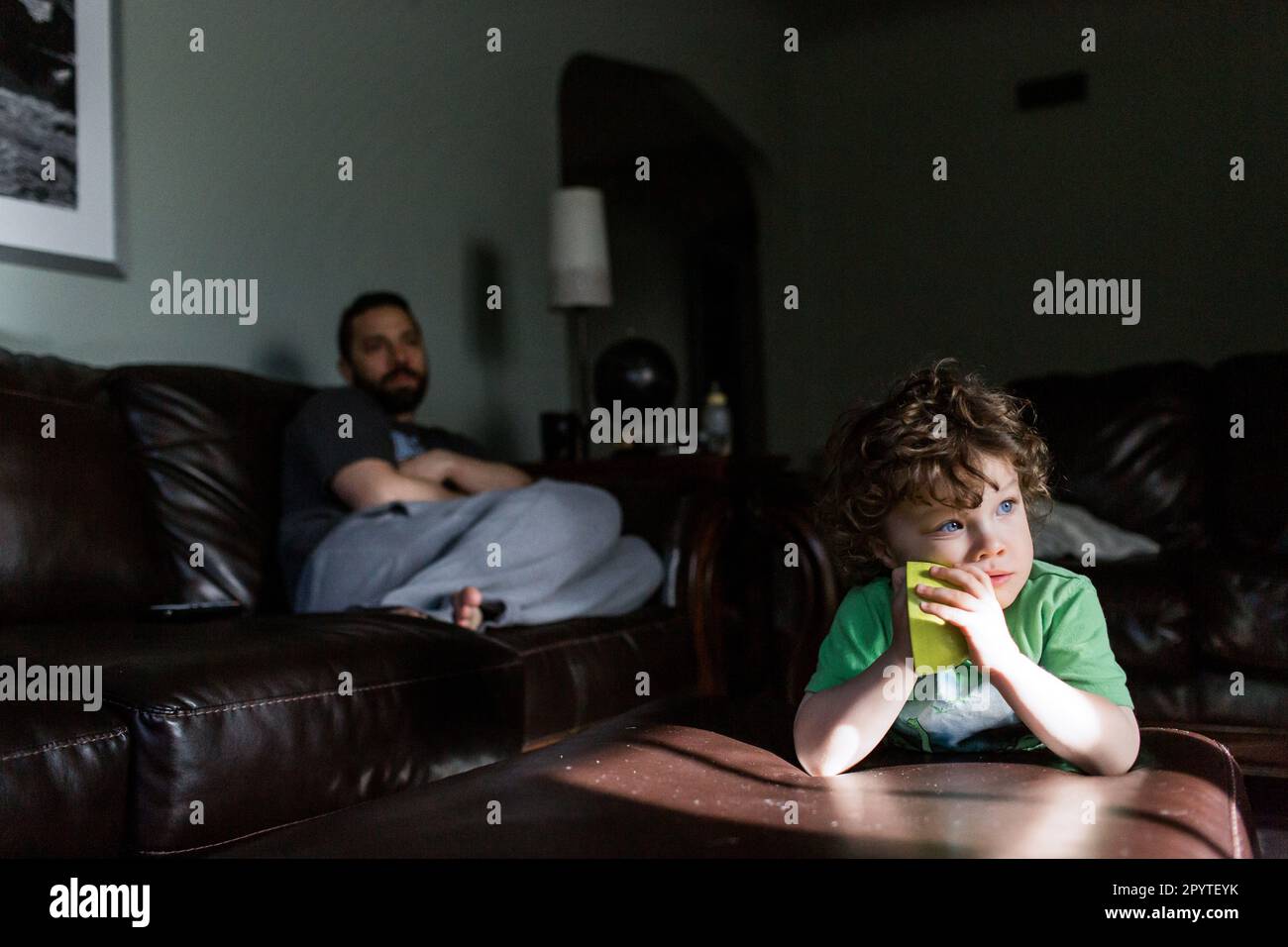 Bambino e genitore che guardano qualcosa nel soggiorno Foto Stock