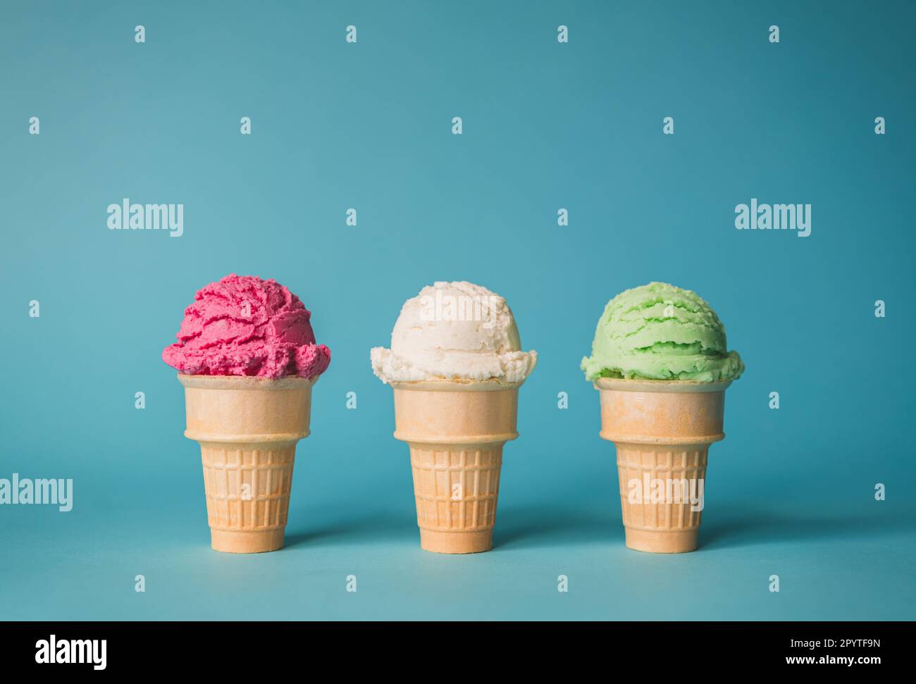 Tre coni di gelato in una varietà di sapori su sfondo blu. Foto Stock