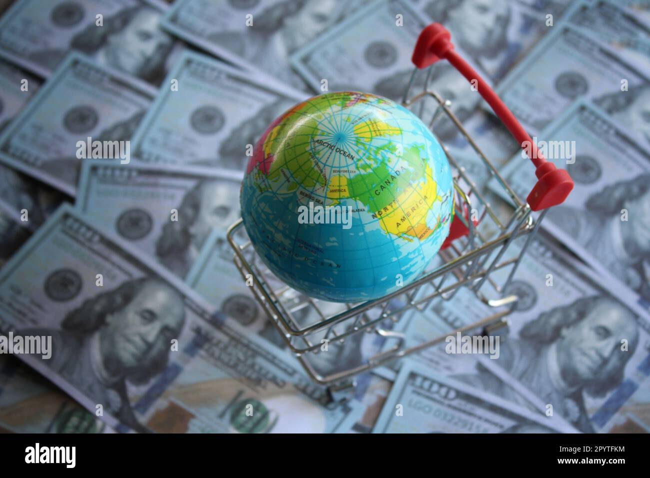 Il globo della terra all'interno del carrello di shopping in cima al denaro. Mercato globale, concetto di business internazionale Foto Stock
