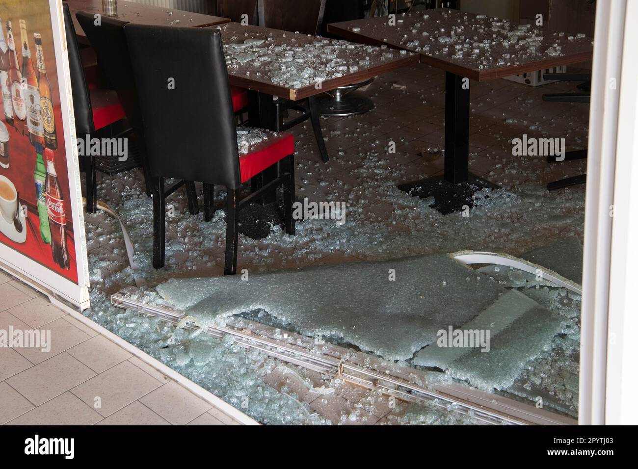 Berlino, Germania. 05th maggio, 2023. Schegge di vetro da una finestra rotta di un ristorante in un centro commerciale a Neu-Hohenschönhausen (Berlino-Lichtenberg) si trovano sul pavimento, tavoli e sedie. La causa fu la detonazione di un bancomat situato nella lobby del centro commerciale. I colpevoli sconosciuti avevano fatto saltare la macchina la mattina presto e hanno causato danni enormi. Un ristorante e un negozio di tessuti sono stati colpiti dal blast. Anche il soffitto del centro commerciale e una serranda a rullo sono stati gravemente danneggiati. Credit: Paul Zinken/dpa/Alamy Live News Foto Stock