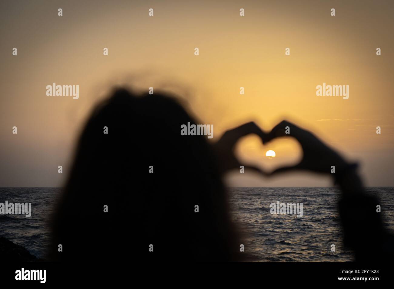 Le mani femminili forma il cuore sulla natura bokeh mare tramonto, tropicale tramonto spiaggia. Copiare spazio di felice amore viaggio e libertà in natura concetto. Foto Stock
