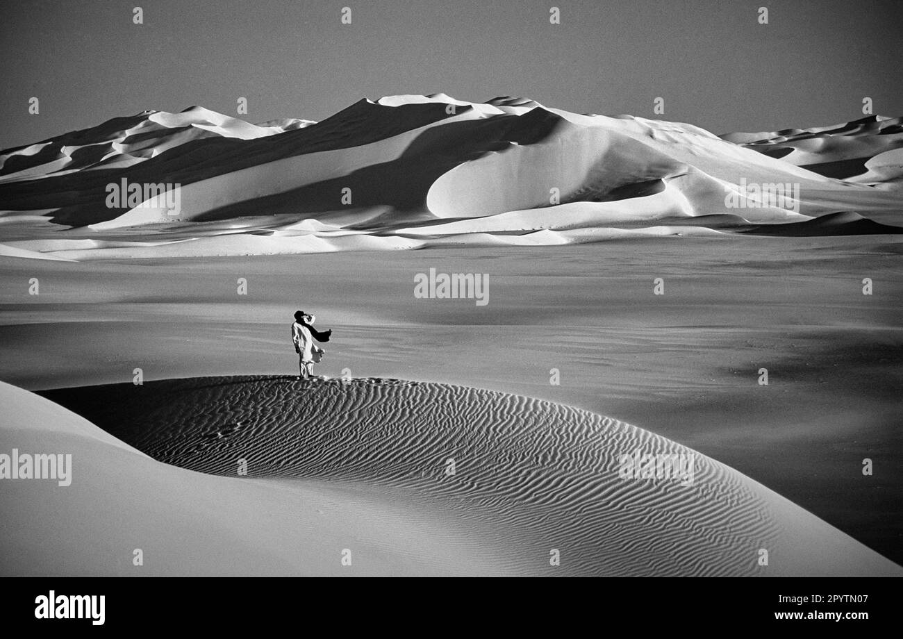 Algeria, vicino a Djanet. Deserto del Sahara. Erg Admer dune di sabbia. Uomo della tribù Tuareg. Bianco e nero. Foto Stock