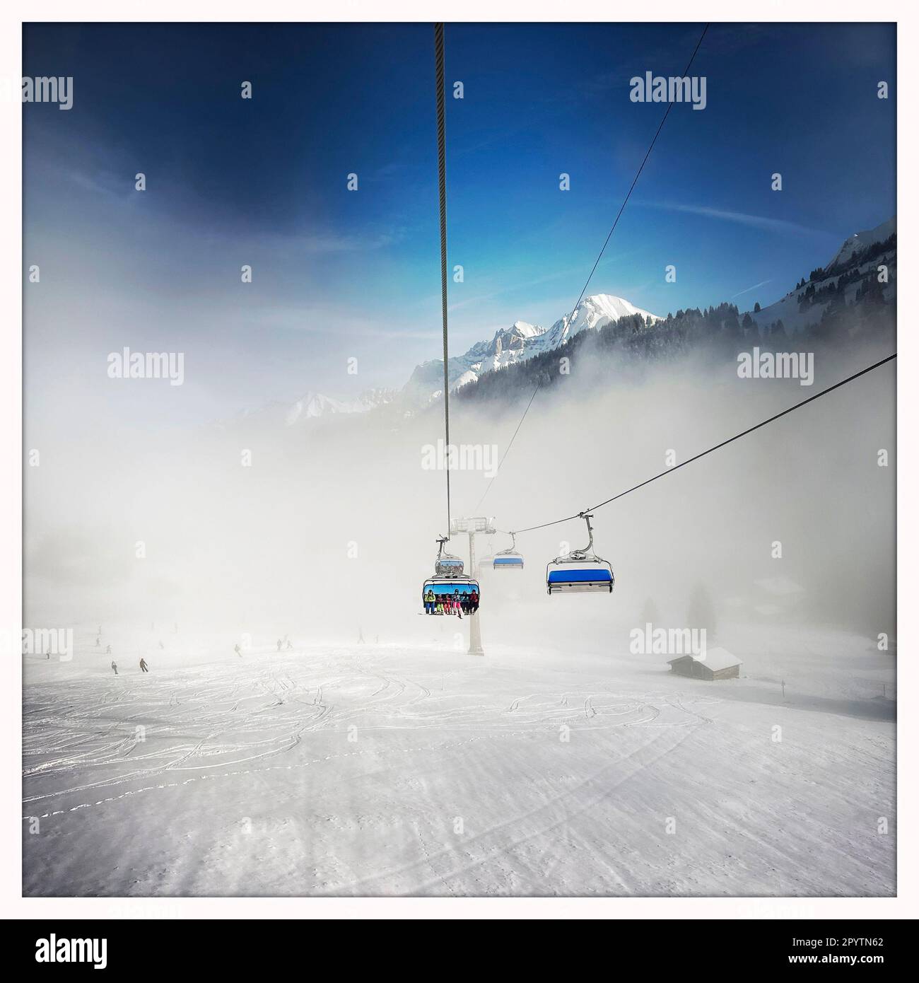 DALLA SERIE ADELBODEN funivia nella neve di fronte al paesaggio invernale a Adelboden, Oberland Bernese, Canton Berna, Svizzera. La pittoresca cittadina di Adelboden è un idillio svizzero nelle Alpi Bernesi, vette impressionanti, paesaggio invernale unico, popolare area sciistica, pascoli alpini, cascate frettolose, accoglienti case in legno. A causa del cambiamento climatico e sempre meno neve, il classico resort degli sport invernali si sta riorientando e la stagione estiva sta diventando sempre più importante Foto scattata con iPhone, l'app Hipstamatic. Foto Stock