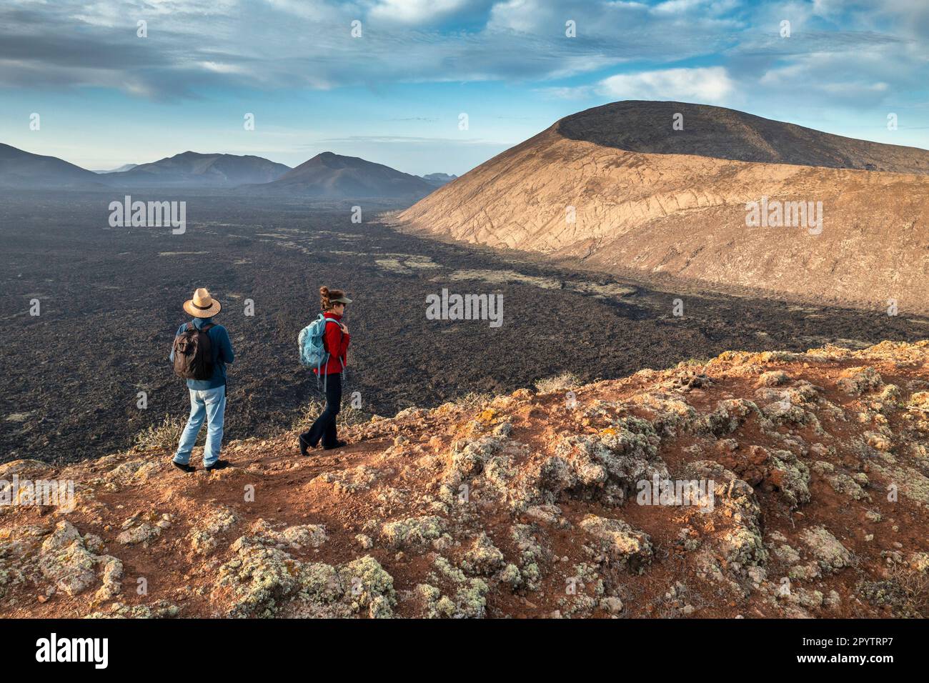 Spagna, Isole Canarie, Lanzarote, Parco Nazionale di Timanfaya, Montagnas del Fuego, Fire Mountains, cratere vulcanico paesaggio. Alba. Escursionisti su C Foto Stock