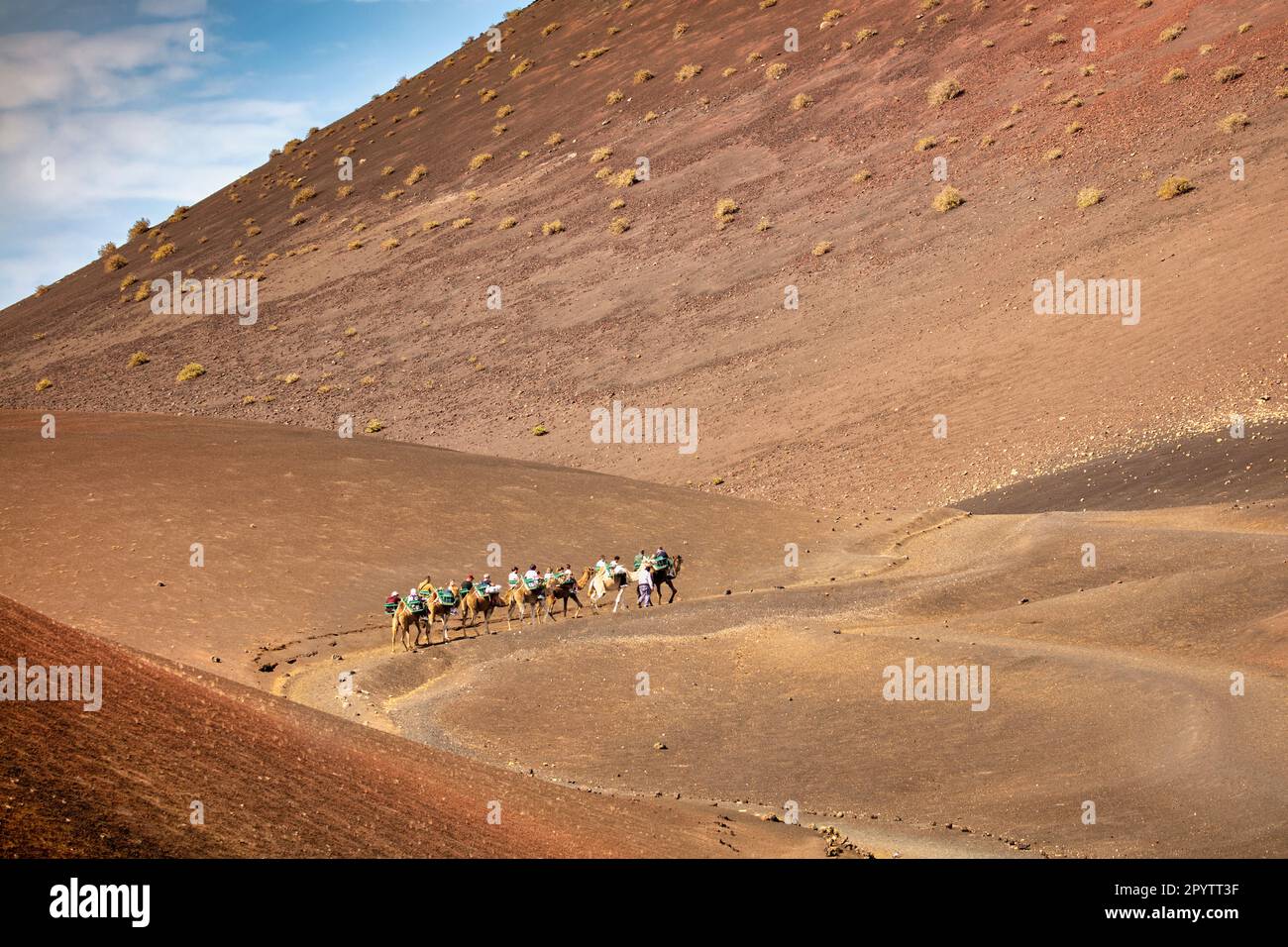 Spagna, Isole Canarie, Lanzarote, Parco Nazionale di Timanfaya, Montagnas del Fuego, Fire Mountains, cratere vulcanico paesaggio. Turisti, giro in cammello Foto Stock