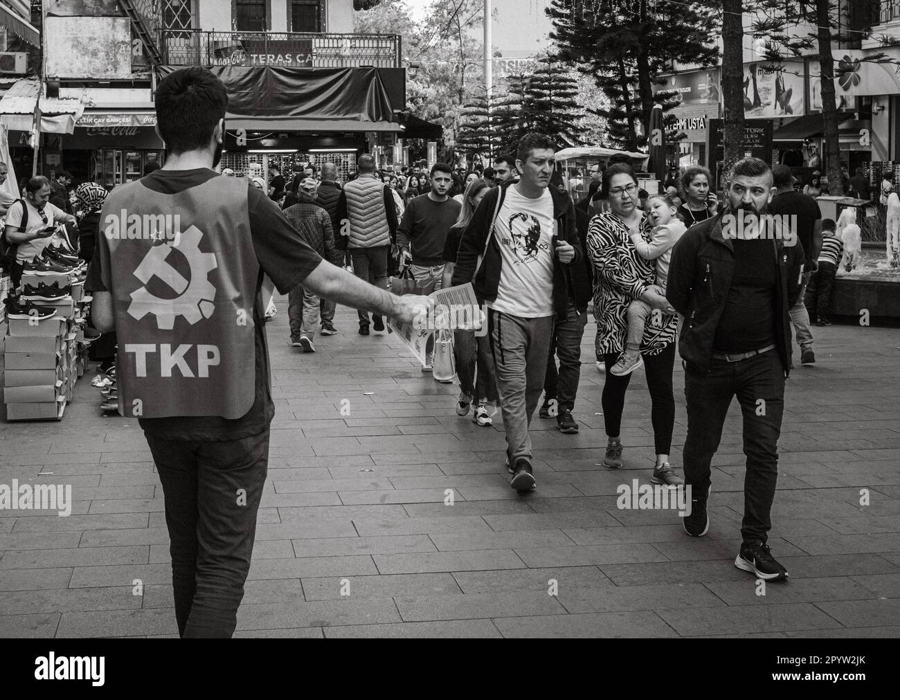 In una vivace via commerciale ad Antalya, Turchia (Turkiye), un membro del Partito comunista turco (TKP) estende il suo braccio per distribuire il fogliame elettorale Foto Stock