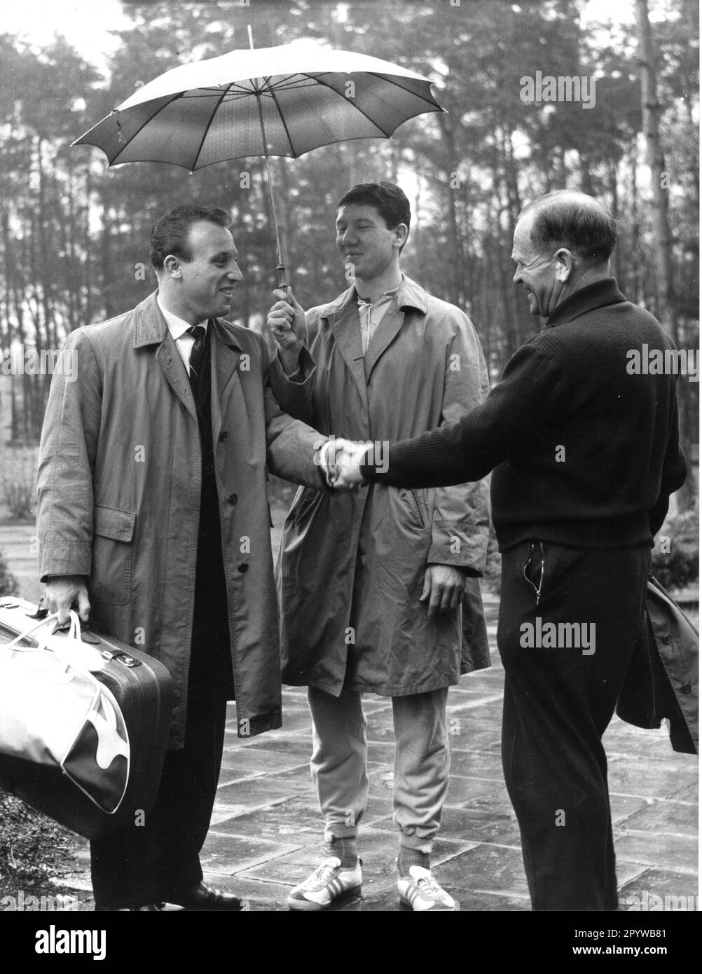 Corso di formazione della nazionale tedesca di calcio a Duisburg-Wedau il 15.11.1960 (stimato). L'allenatore nazionale Sepp Herberger dà il benvenuto a Uwe Seeler. Szymaniak (al centro) tiene l'ombrello. Solo per uso giornalistico! Solo per uso editoriale! [traduzione automatica] Foto Stock