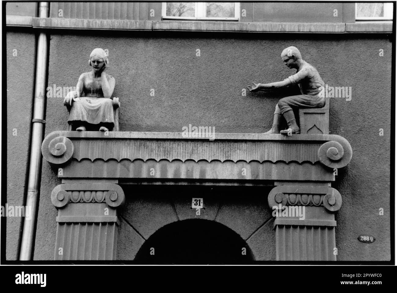 Zittau, Germania orientale, ex RDT. Facciata della casa, arte in costruzione. Vista parziale: Uomo e donna come scultura in pietra, vita quotidiana, figure sopra il portale d'ingresso. Vista sulla città, in bianco e nero. Foto, 1992. Foto Stock