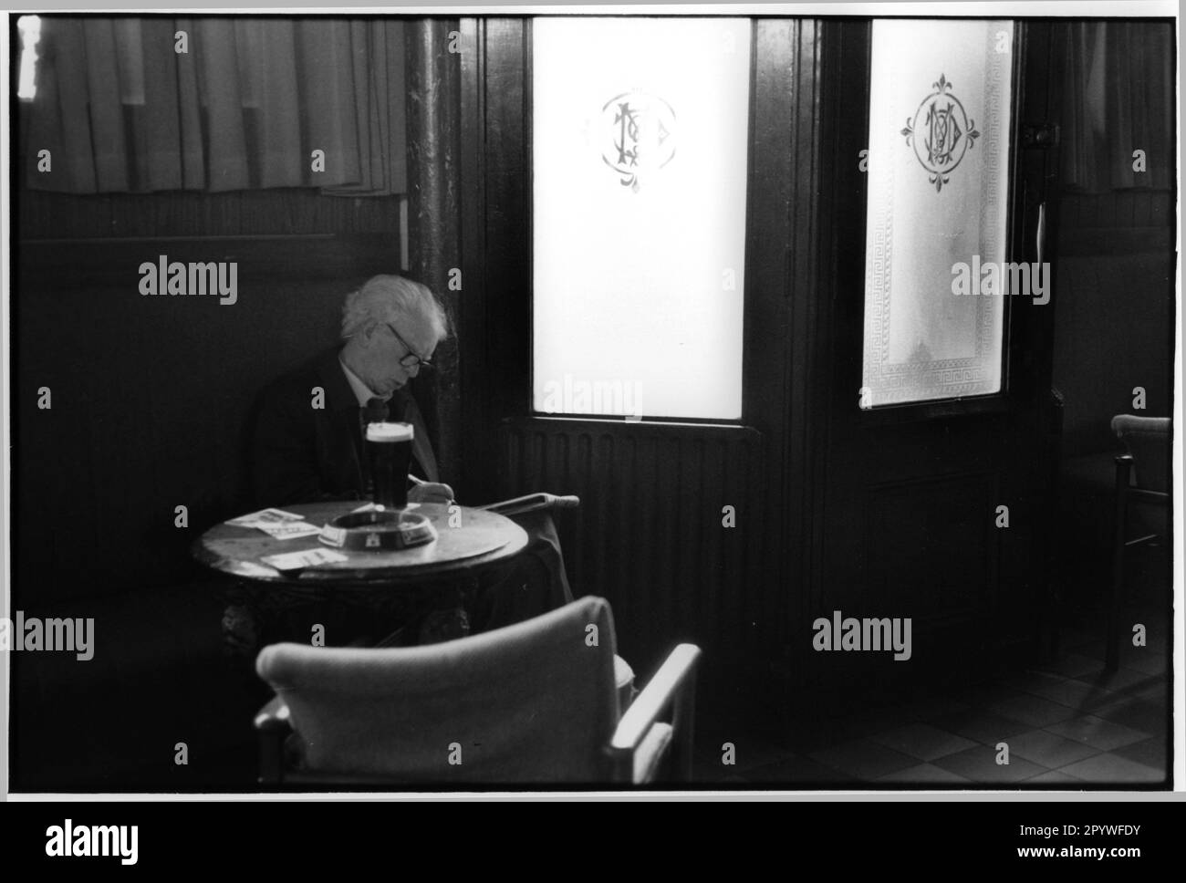 Gastronomia: Birreria e come Un ospite siede da solo ad un tavolo in un pub a Dublino, Irlanda. Sta leggendo e ha davanti a sé un bicchiere di birra Guinness. Scenografia, bianco e nero. Foto, 1992. Foto Stock