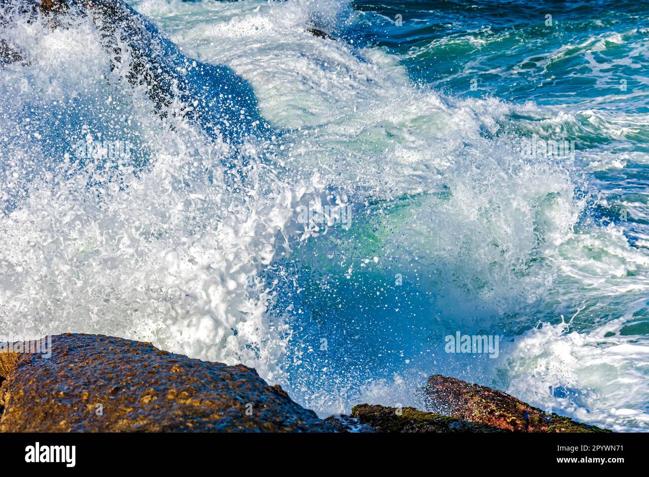 Onda che si schiantano contro le rocce con acqua di mare che spruzzi in aria, Brasile Foto Stock