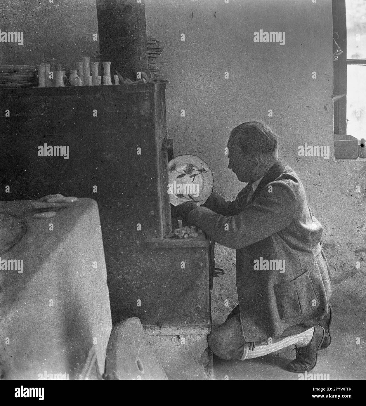 Uomo in una manifattura di porcellana in terra Berchtesgadener. Toglie un piatto dal forno. Foto non datata intorno al 1935. Foto Stock