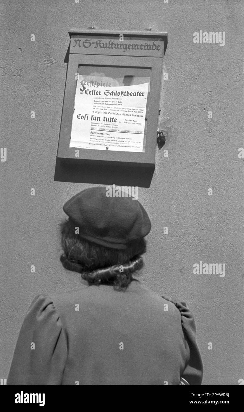 Una donna sta in piedi di fronte a una bacheca dello Schlosstheater celle, annunciando un'esecuzione dell'opera di Mozart cosi fan tutte. Foto Stock