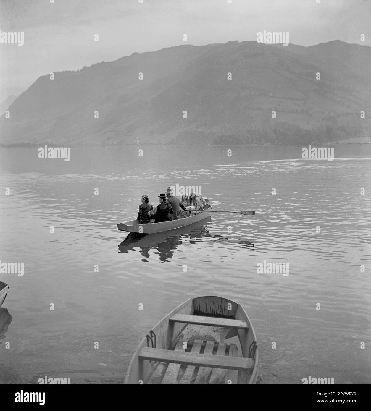 Persone in barca sulla riva del Lago di Zell. Sullo sfondo un caffè e un posto barca ormeggio. La famiglia è sulla strada per un St. Festa di Maria a Zell. Foto Stock