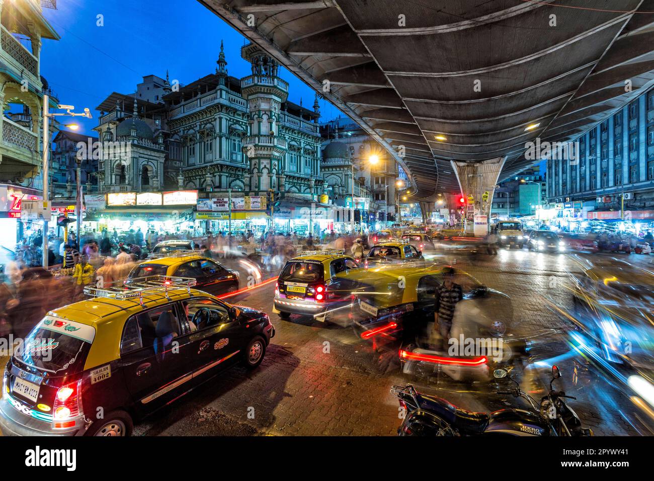 Ora di punta con taxi di fronte alla moschea Minara Majid, vita urbana in serata, vista della città dalle strade del quartiere dominato dai musulmani di Foto Stock